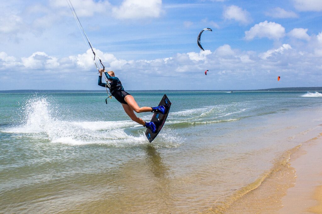 A woman kitesurfs, soaring above the water along the coast of Sri Lanka, an exhilarating water sport offered by Ceylon Roots, a premier Tour Company in Sri Lanka and experienced Tour Operators in Sri Lanka.