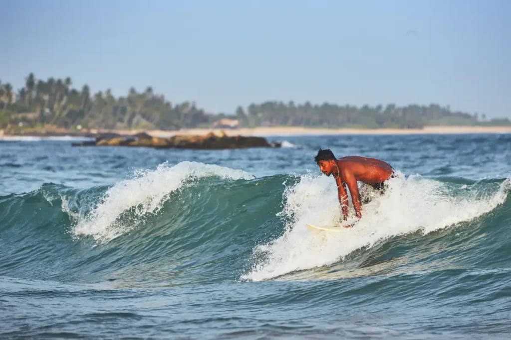 A man surfing a wave in Sri Lanka, an adventure sport offered by Ceylon Roots, a leading Tour Company in Sri Lanka and one of the best Tour Operators in Sri Lanka.