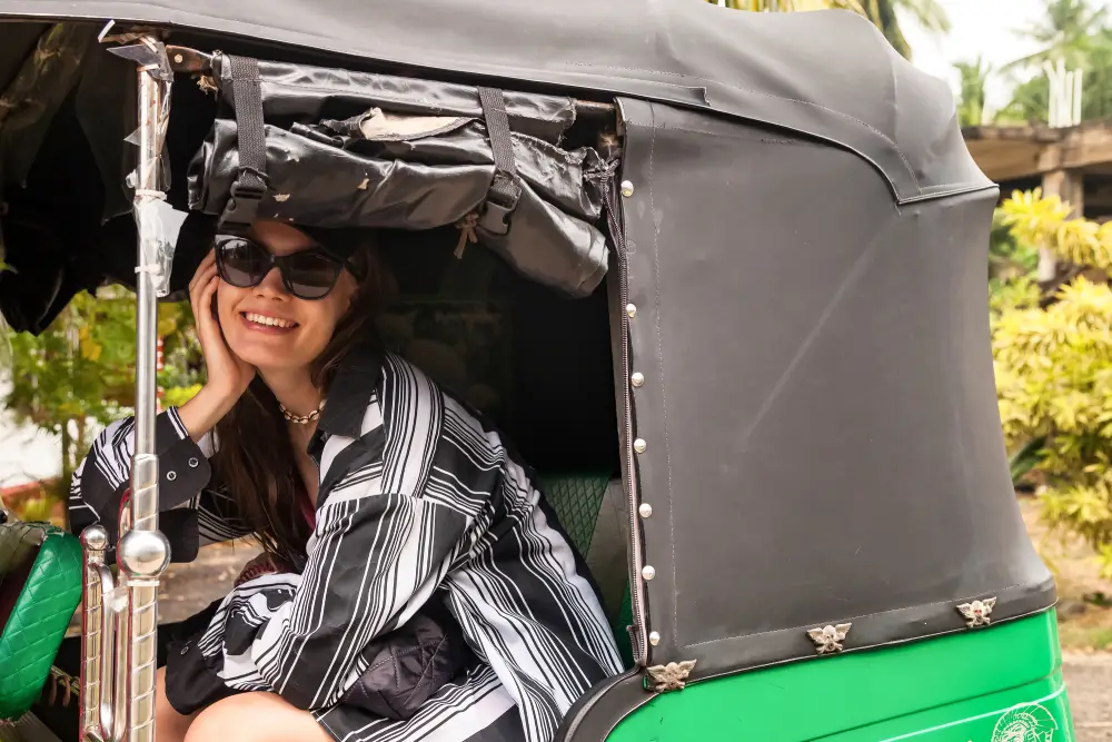 A happy tourist smiles while riding in a green tuk-tuk, a popular and authentic mode of transport for exploring Sri Lanka. This local experience is often a highlight of city and village tours arranged by the best Tour Operators in Sri Lanka and a professional Tour Company in Sri Lanka.